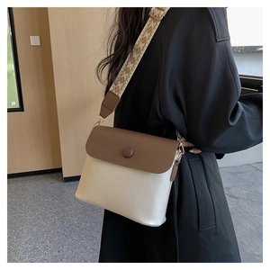 Detail view of stylish crossbody bag featuring a wide geometric pattern woven strap