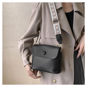 Detail of minimalist black crossbody bag with colorful geometric woven shoulder strap