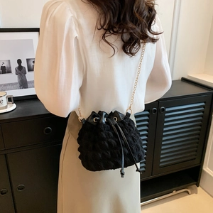 Sac seau noir tendance avec texture à bulles et bandoulière chaîne porté par un mannequin