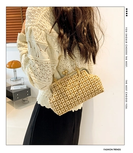 Detail of vintage woven clasp handbag with gold metal frame worn with beige knitwear