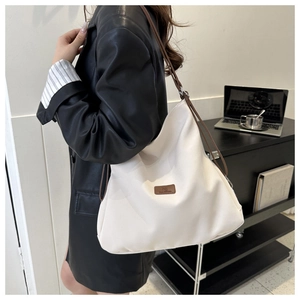 Close-up of a stylish off-white tote bag with brown straps worn by a model in an office
