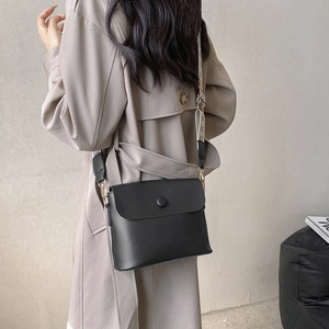 Minimalist black matte crossbody bag with wide jacquard strap and gold hardware on a model