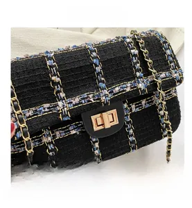 Détail de la texture en tweed noir et du fermoir rotatif doré sur le petit sac carré