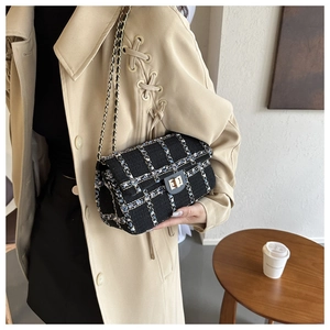 Détail de la texture en tweed et du fermoir doré sur un sac à chaîne chic