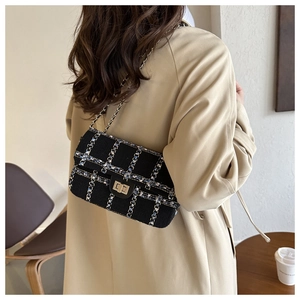 Détail d'un sac bandoulière en tweed noir avec fils d'argent et chaîne en métal sur un modèle