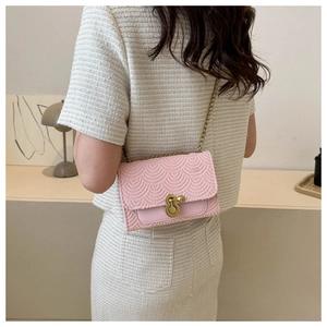 Détail du sac bandoulière rose clair avec texture écailles et fermoir boule dorée