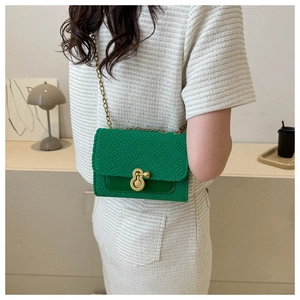 Vue détaillée d'un sac matelassé vert avec chaîne dorée porté par un mannequin