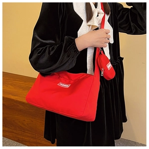 Detail view of a red nylon crossbody bag with an attached round coin purse on strap
