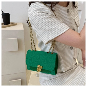 Détail du sac bandoulière vert vif avec texture écailles et chaîne dorée sur mannequin