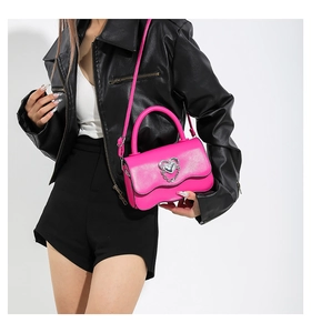 Detail of rose pink handbag with silver heart buckle and wavy edge flap design