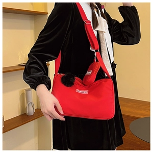 Detail of red crossbody pillow bag with black fur ball and mini purse attachment