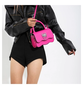 Detail of neon pink mini crossbody bag with heart clasp and wavy flap design