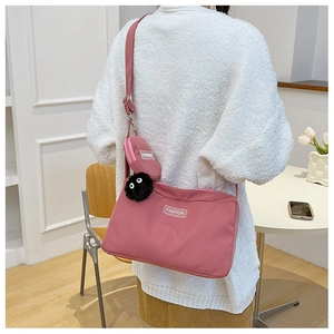 Detailed shot of pink nylon crossbody bag with matching pouch and black soot sprite charm