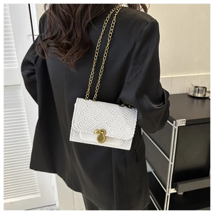 Détail d'un sac blanc à texture gaufrée avec chaîne dorée et fermoir rotatif rond chic