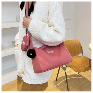 Pink nylon crossbody bag set featuring a matching coin purse and plush charm on a model