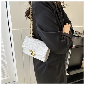 Détail du sac à bandoulière blanc avec texture ondulée et fermoir anneau doré sur costume noir