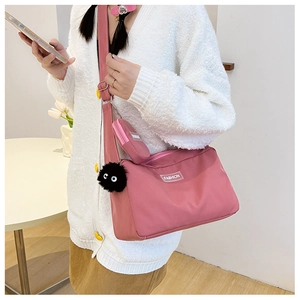Detail of pink nylon crossbody bag with fashion label and plush eyeball charm accessory