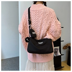 Detail of black nylon crossbody bag set with small pouch and plush doll charm