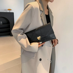 Pochette noire élégante avec coutures géométriques et boucle coeur en métal doré
