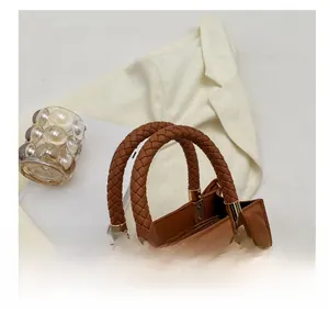 Close-up of woven handle and quilted texture on a brown shoulder bag with gold hardware