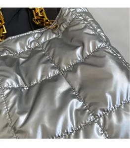 Detail of silver quilted tote bag featuring metallic gloss fabric and gold chain strap