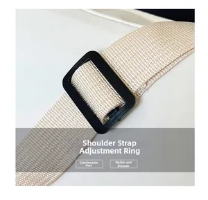 Detail of adjustable nylon strap and black plastic buckle on a beige crossbody bag