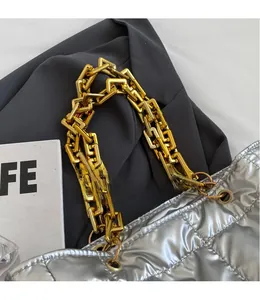 Detailed shot of metallic silver quilted tote featuring thick gold chain strap hardware