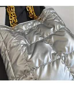 Close-up of silver quilted tote bag featuring metallic finish and gold chain strap detail