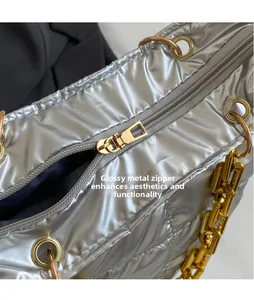 Macro view of silver quilted fabric tote bag with smooth gold zipper pull and chain