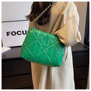 Detail of green quilted handbag with geometric stitching and chunky gold chain strap