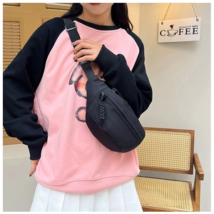 Detail of durable black nylon crossbody bag with adjustable wide strap and woven zipper puller