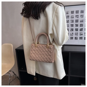 Detail of beige quilted chain bag with unique braided handle and gold metal hardware