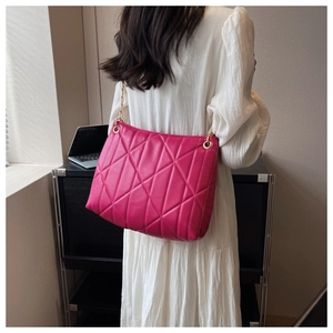 Detail of bright pink quilted shoulder bag with gold chain strap on white dress