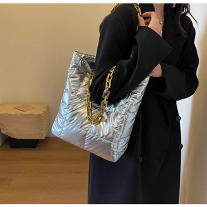 Detail of silver quilted tote bag with gold chain strap on a black winter coat