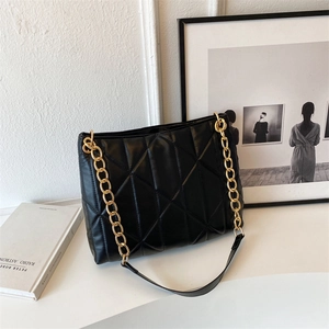 Detail of black quilted shoulder bag featuring premium texture and gold chunky chain strap
