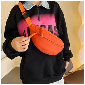 Detail of bright orange crescent bag featuring woven rope zippers and adjustable buckle