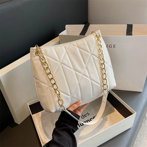 Detail of white quilted handbag featuring premium diamond stitching and gold chain strap