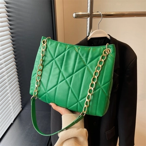 Detail of bright green quilted tote bag with chunky gold chain strap and PU leather finish