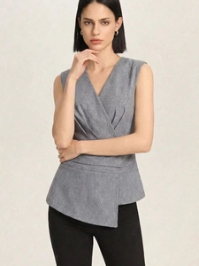 Detail of grey sleeveless wrap top featuring V-neck, waist pleats and asymmetric peplum hem