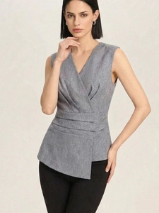 Detail of gray sleeveless wrap top with elegant waist pleats and asymmetric hemline