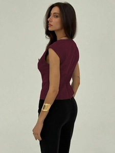Side view of a slim-fit sleeveless burgundy vest top paired with black high-waisted pants