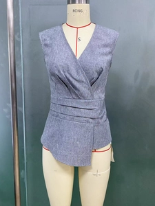 Close-up of grey sleeveless wrap top featuring a V-neck and triple waist pleats detail