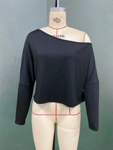 Dettaglio della maglia nera a maniche lunghe con scollo asimmetrico e spalla scoperta