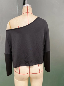 Dettaglio del top nero monospalla a maniche lunghe con patchwork in maglia su manichino