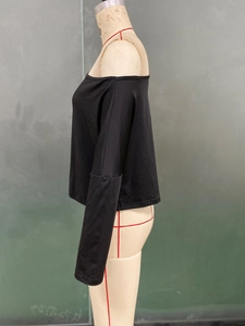 Dettaglio di un top nero a maniche lunghe con spalle scoperte su un manichino sartoriale
