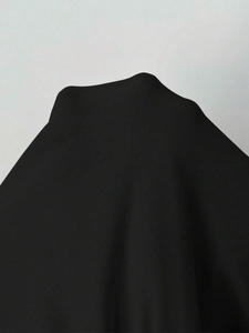 Détail du tissu extensible noir à côtes sur cette robe ajustée à manches longues