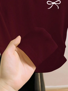 Dettaglio del polsino rosso vino a maniche lunghe con stampa a fiocco bianco e trama a maglia
