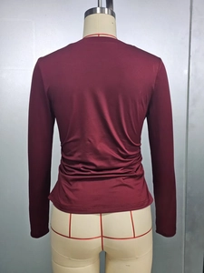 Dettaglio del design arricciato in vita di un top slim fit bordeaux a maniche lunghe