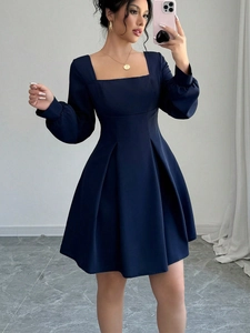 Detail view of square neck puff sleeves and pleated waist on navy blue A-line dress