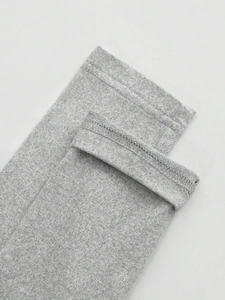 Dettaglio del tessuto grigio mélange con doppie cuciture di precisione e rifinitura overlock